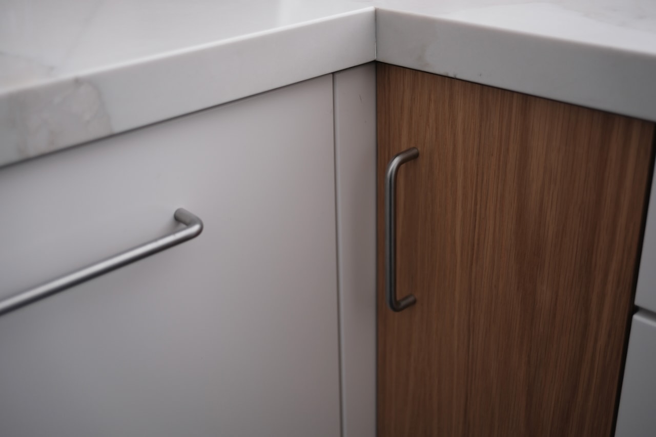 Bar pulls on a white door and a white oak door at a kitchen corner.
