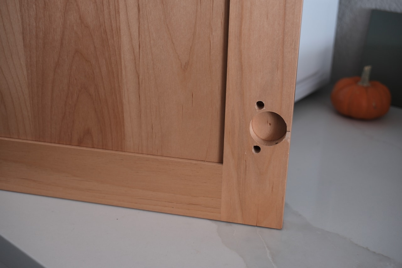 A maple shaker door with a hinge cup bored near its edge.